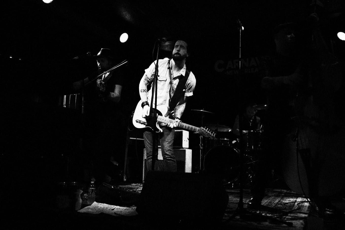 Aden Paul playing acoustic guitar alone in a shaft of stage light